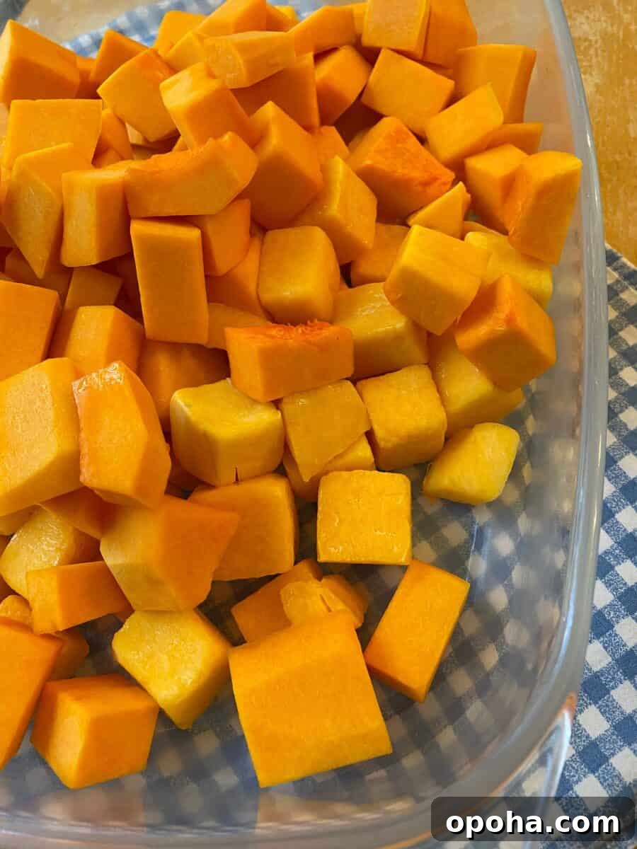 Diced butternut squash spread out in a glass baking dish on a placemat.