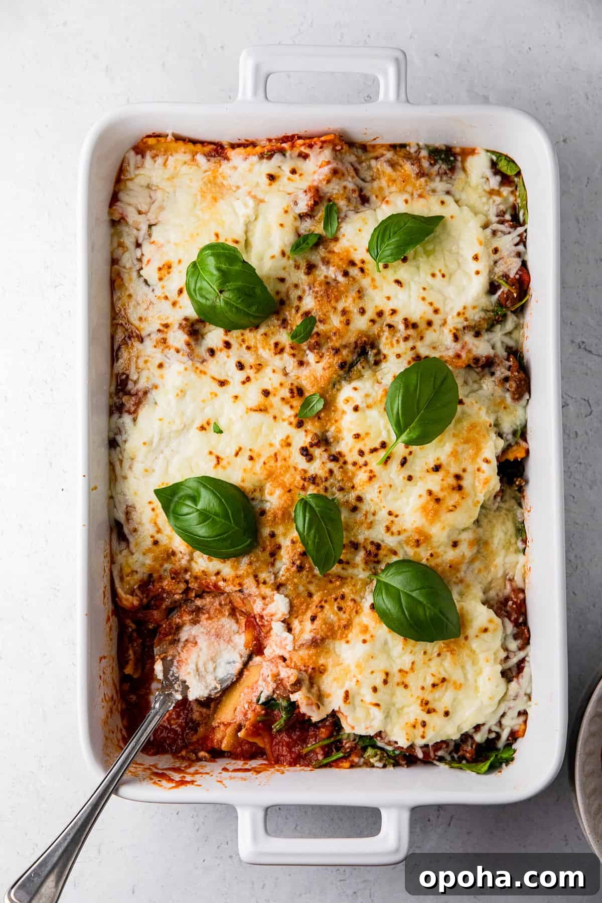 spinach ricotta ravioli dish with baked ravioli and basil leaves