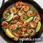 Skillet with seared shrimp, herbs, wine sauce and lemon wedges.