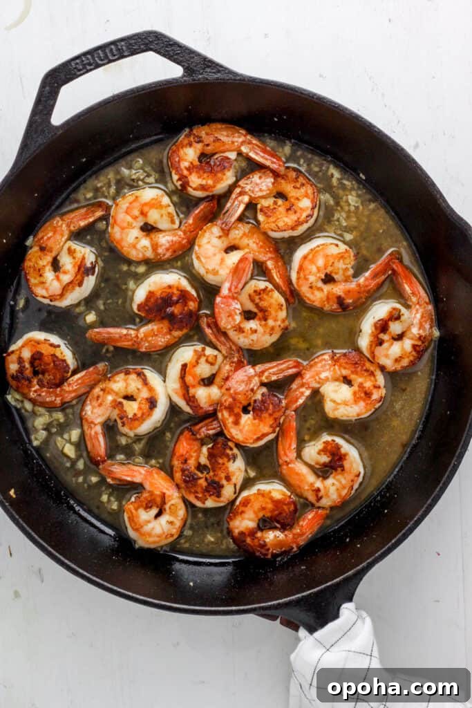 skillet with seared shrimp and a white wine sauce.