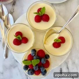 Four lemon posset custard dessert cups topped with fresh berries.