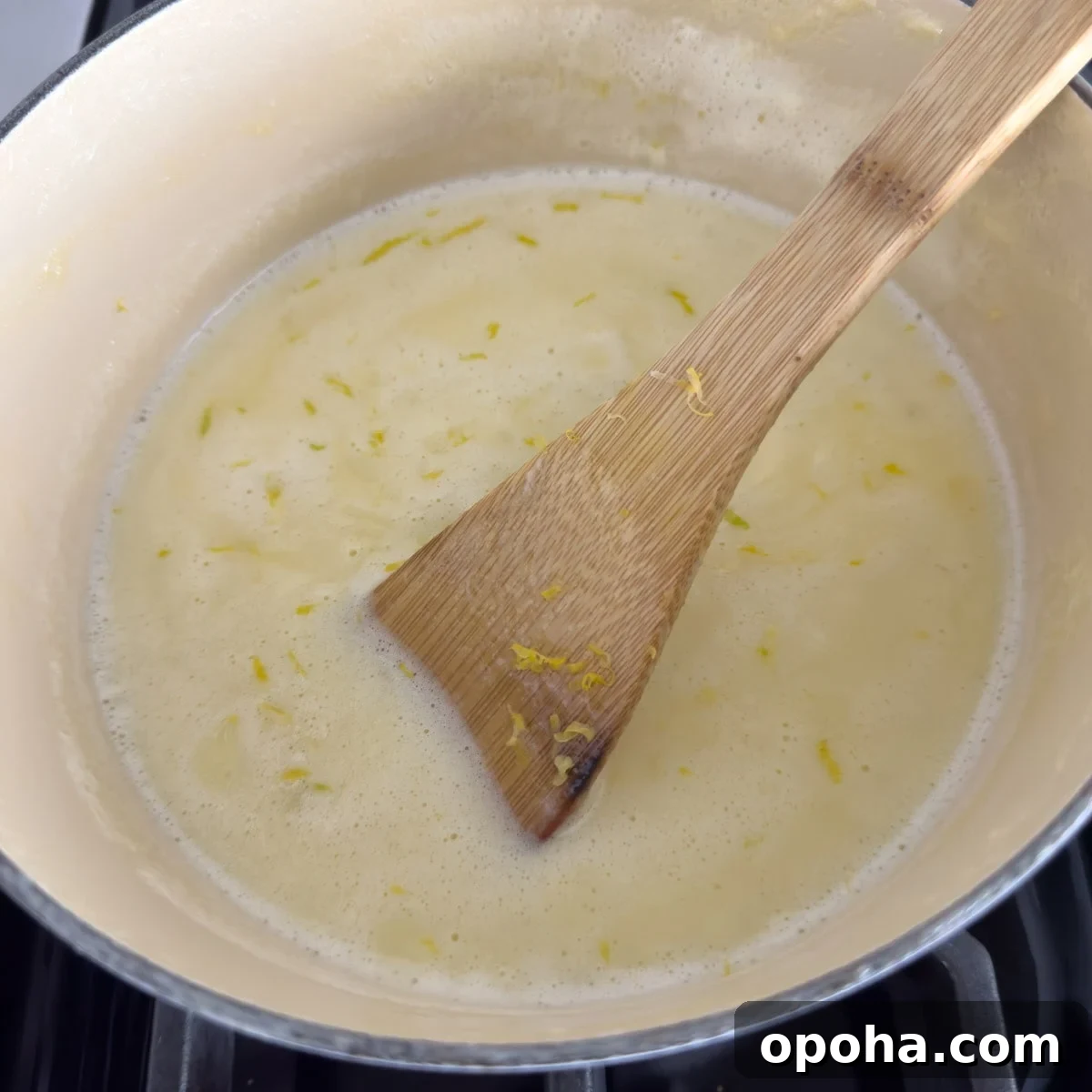 A pot of heavy cream and lemon zest on the stovetop.