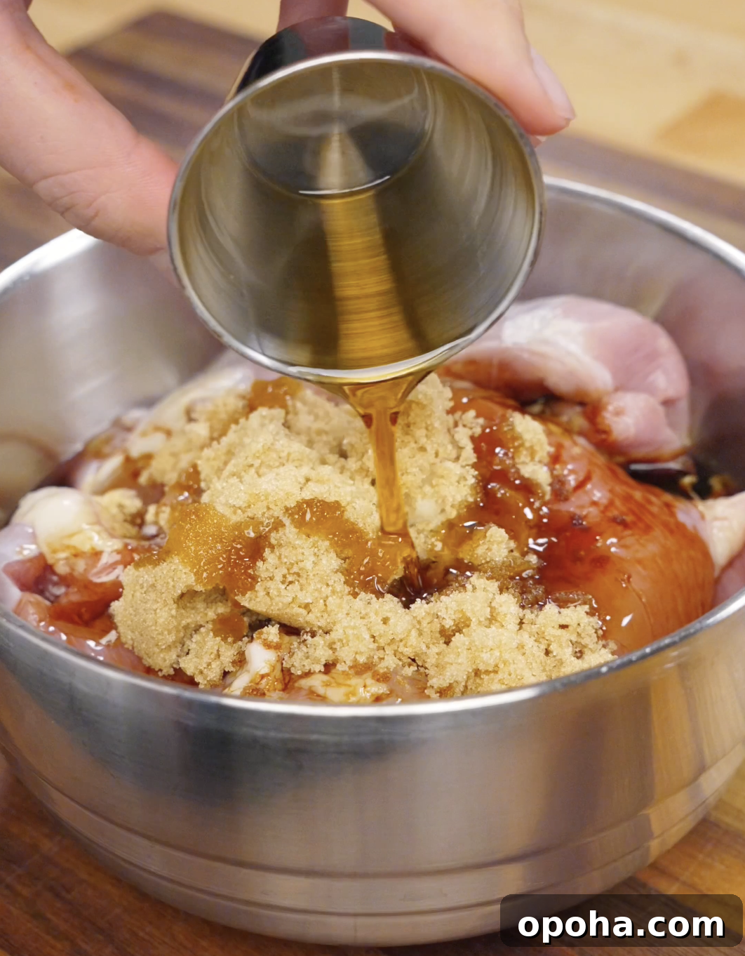 Honey being poured over chicken thighs in a bowl with soy sauce, gochujang, garlic, and brown sugar to create a sweet and savory Korean bulgogi marinade.