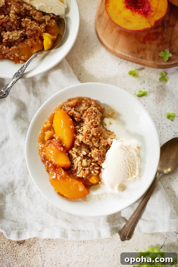 peach crisp with oatmeal topping on a plate with vanilla ice cream