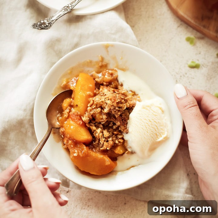 woman eating a bowl of easy peach crisp with vanilla ice cream