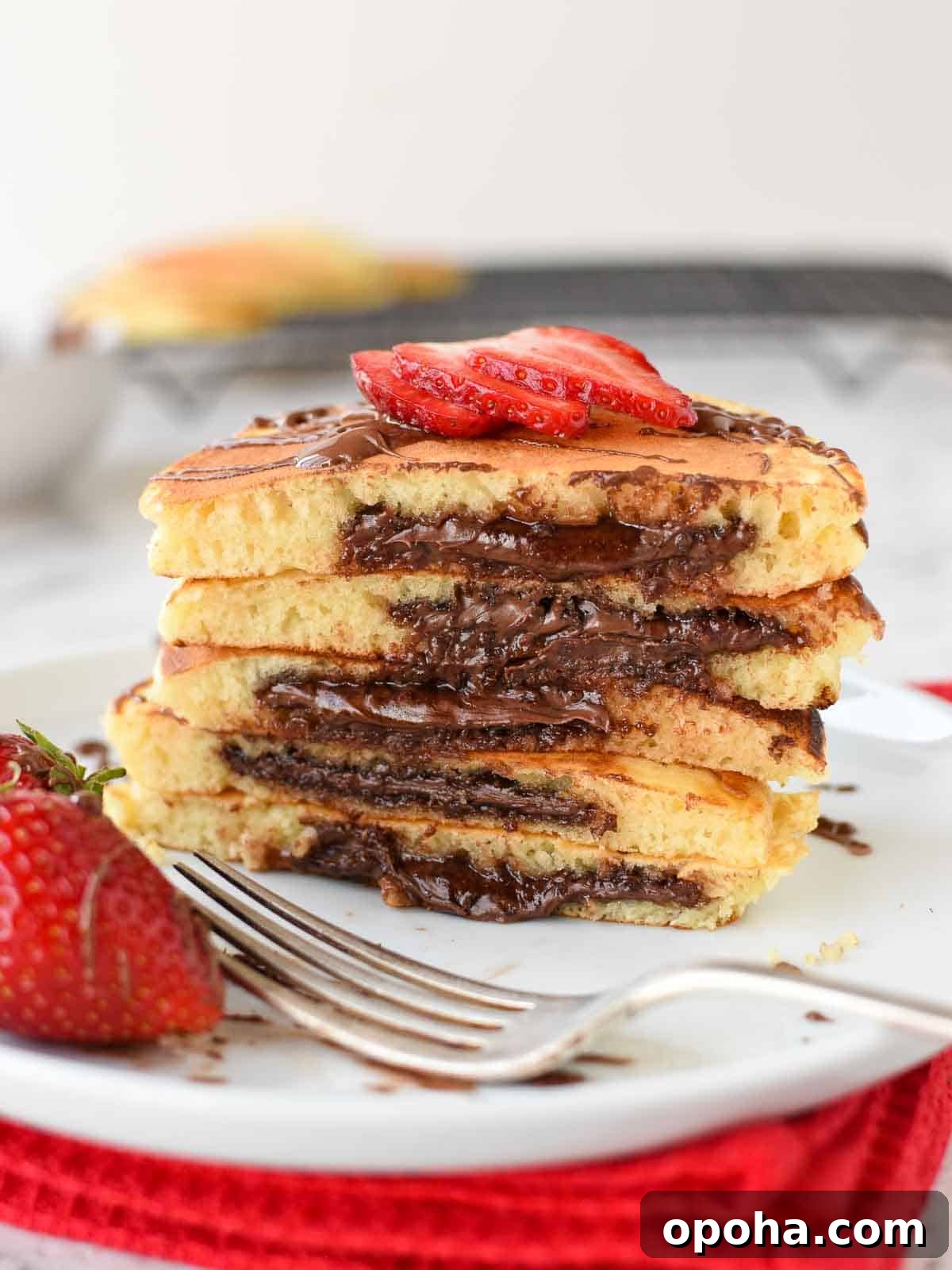 Fluffy Nutella-Stuffed Pancakes 2 Nutella pancakes cut in half and stacked on a white plate.