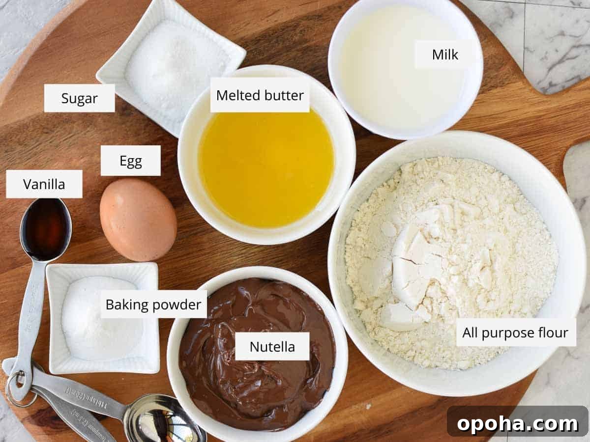 Fluffy Nutella-Stuffed Pancakes 3 Sugar, melted butter, milk , flour, nutella, baking powder, egg and vanilla in bowls viewed from above.
